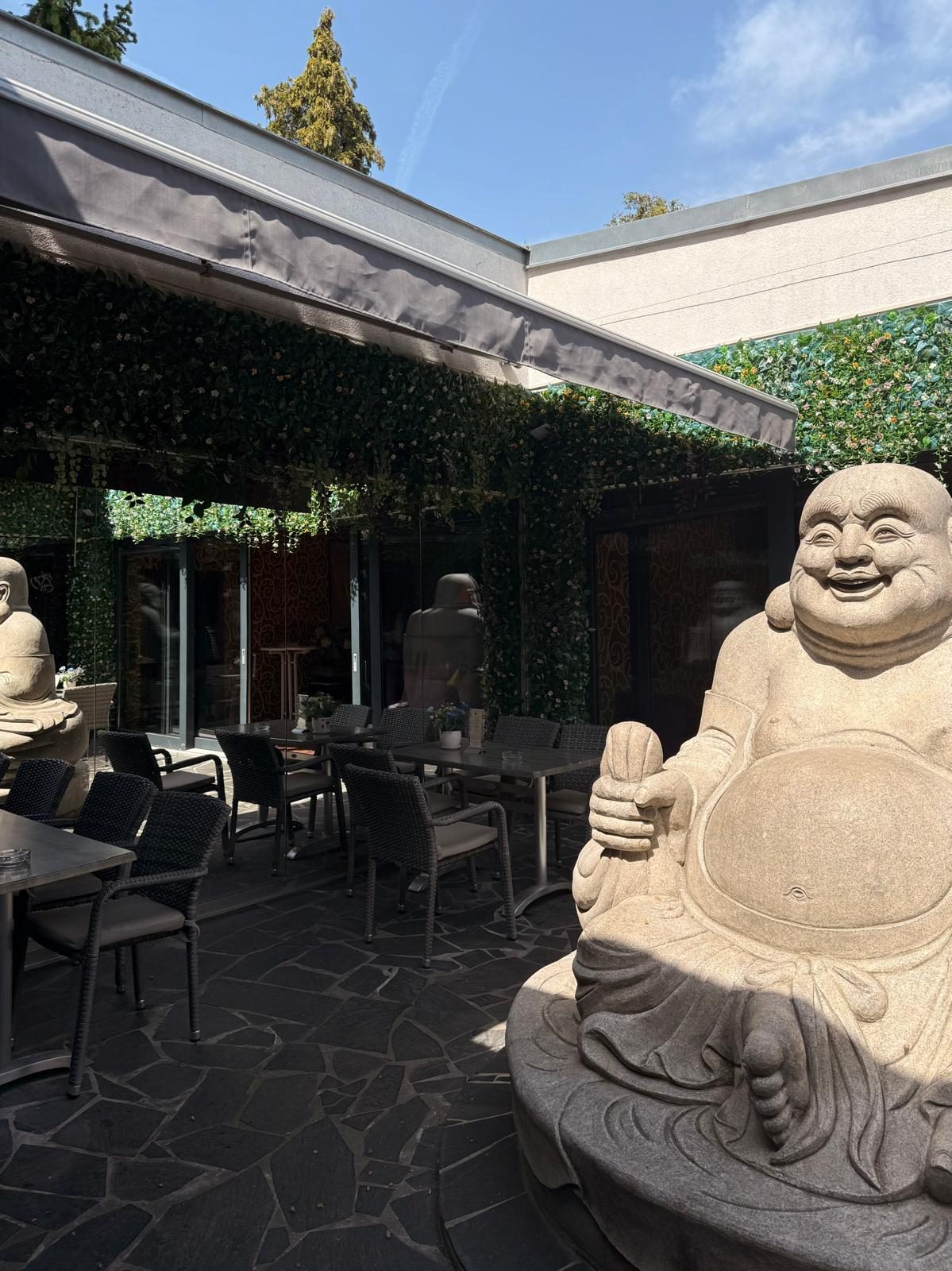 Sonnige Gartenterrasse mit Buddha-Statuen